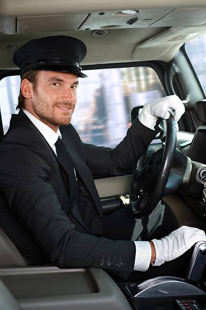 Elegant young chauffeur driving limousine, smiling.